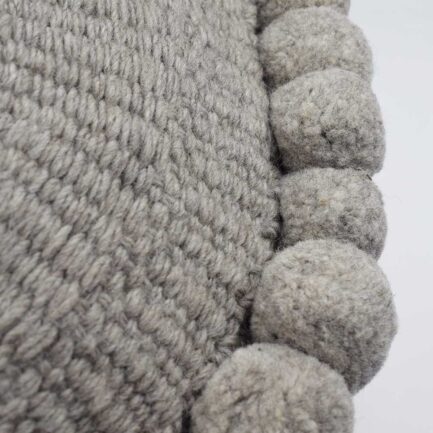 Coussin rond à pompons gris